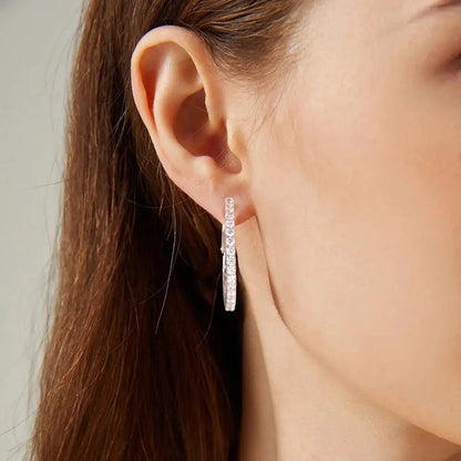 Earring hoops made of sterling silver with cubic zirconia stones. rhodium-plated. Pictured on a models ear