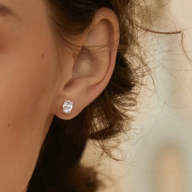 Oval Studs, Made of sterling silver and rhodium plated with cubic zirconia. Pictured on a models ear.